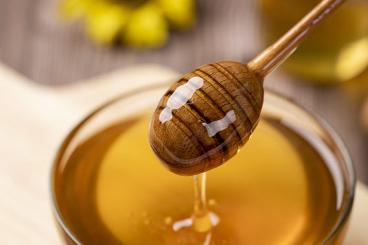 A jar of honey with a honey stick